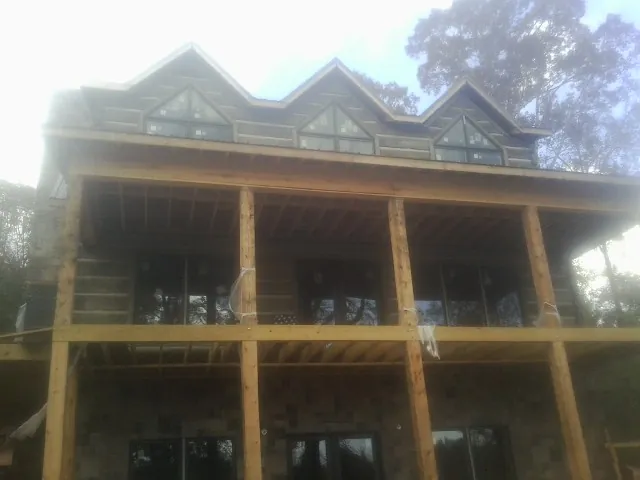 Dormers and porch framing on a large log home under construction — Roof Coating work by our crew in South Burlington