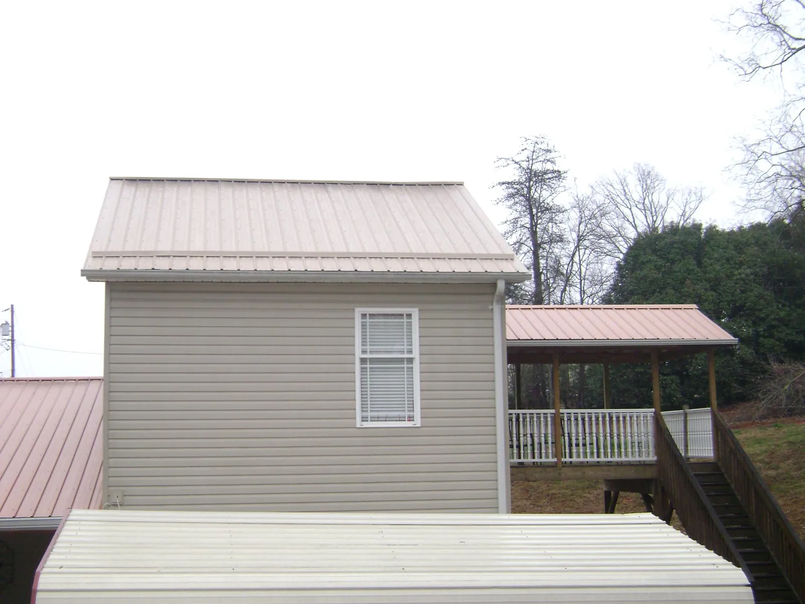 Tan metal roofs on a two story addition and attached porch, from a Roof Replacement job in South Burlington