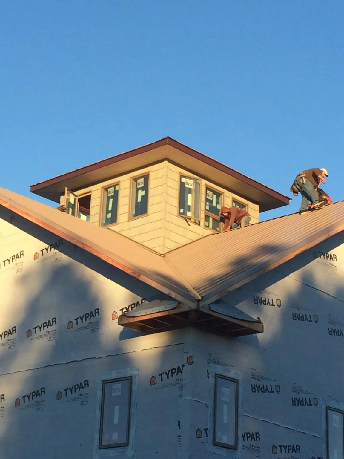 Roofers working around a rooftop cupola on a new metal roof at sunset — Roof Waterproofing in South Burlington by Roofing Brothers